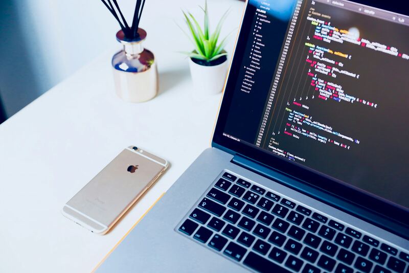 Code on a laptop next to a phone, ready to ship